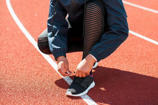 A person on a track tying a running shoe